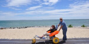 Jean Townes pushes Sharon Crooker during the Mobi Chair's maiden voyage on Pay Beach.